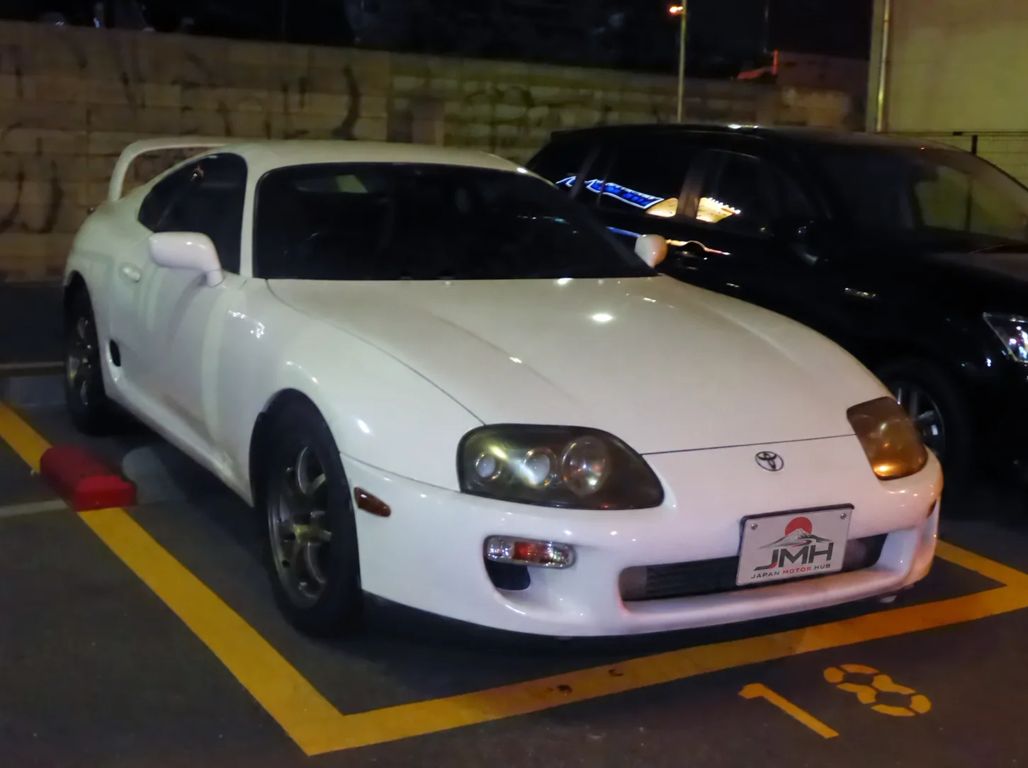White Toyota Supra A80 parked at night with a JMH display plate